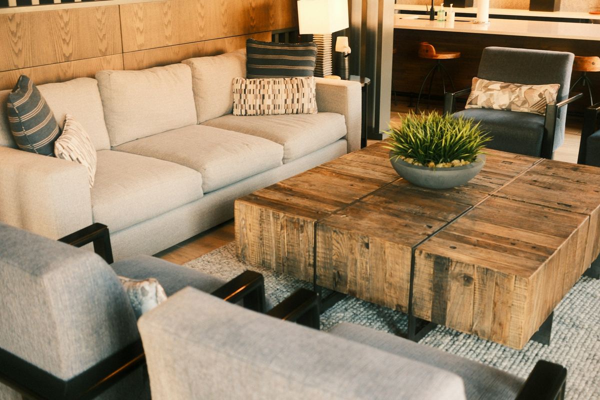 Een woonkamer met een lichte hoekzetel en een houten salontafel
